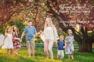 Family walking and laughing under cherry blossoms in West Chester PA during spring family photo session