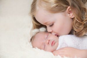 Big sister kissing newborn baby in-home newborn session in West Chester PA