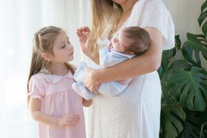 big sister looking at new baby brother